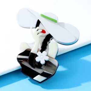 Detailed macro shot of an elegant acrylic girl brooch featuring a white hat and floral detail
