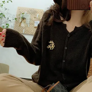 Close-up detail of a vintage gold baroque brooch pinned on a brown knit cardigan.