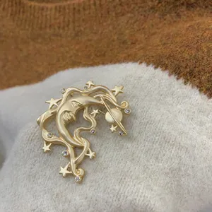 Detailed view of a vintage baroque gold brooch featuring a crescent moon and stars.