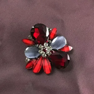 Close-up detail of a vintage Baroque brooch featuring deep red gems and grey stones