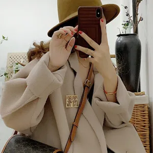 Detail showing a vintage gold baroque palace style brooch pinned on a beige wool coat