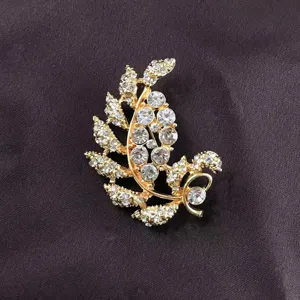 Close-up of a vintage Baroque gold-toned leaf brooch with sparkling clear rhinestones.
