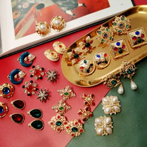 Collection of vintage Baroque earrings with colorful gemstones and pearls on a gold tray.