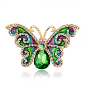 Detailed macro view of vintage butterfly brooch with green crystal and colorful enamel