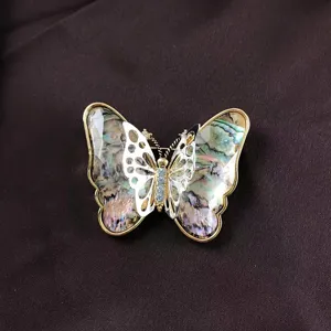 Close-up of vintage Baroque butterfly brooch featuring iridescent shell wings and gold trim