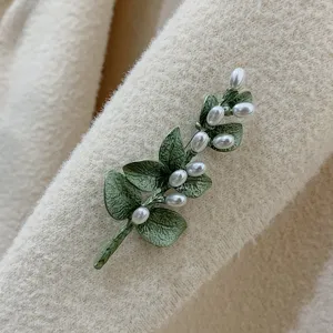 Detail view of a vintage Baroque style brooch with green leaves and white pearls