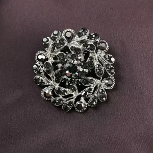 Close-up of vintage baroque brooch with sparkling black rhinestones on dark fabric