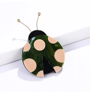 Detalle de un lindo broche de mariquita de mármol verde con elegantes antenas doradas