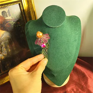 Dettaglio di spilla a fiore vintage con cristalli e perla su espositore
