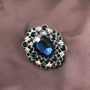Detail view of a vintage baroque brooch featuring a large oval blue crystal center