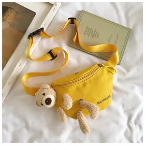 Detail view of yellow canvas bear chest bag on white bedding with props