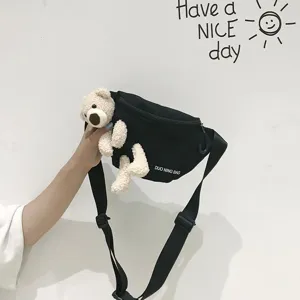 Close-up of a black canvas chest bag featuring a cute plush teddy bear decoration
