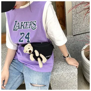 Detail view of a black canvas waist bag featuring a cute plush bear attached for a casual style