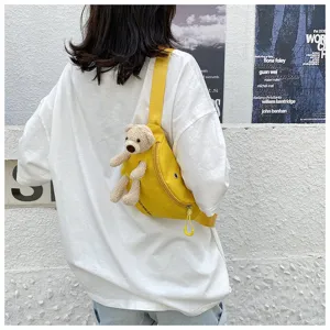 Yellow canvas chest bag with a cute plush bear ornament worn by a model in detail