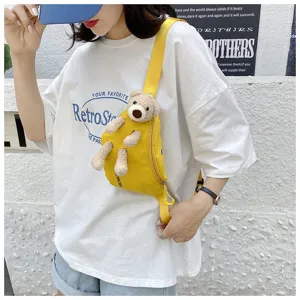Close-up of a model wearing a vibrant yellow canvas chest bag with a 3D plush bear