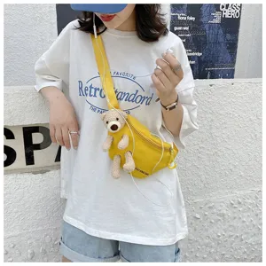 Detailed view of a yellow canvas chest bag featuring a cute 3D plush bear ornament