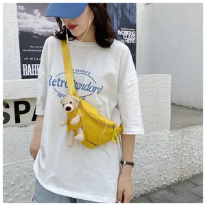 Detail showing a stylish yellow canvas chest bag with a cute plush bear accessory attached