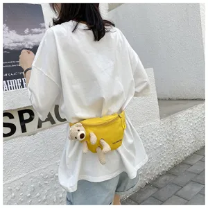 Close-up of a yellow canvas waist bag featuring a cute plush bear decoration on a model