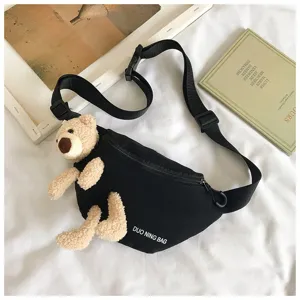 Close-up of black canvas chest bag featuring a cute 3D plush teddy bear accessory.
