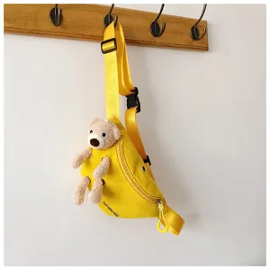 Detail view showing a bright yellow canvas chest bag featuring a cute plush teddy bear