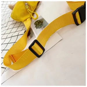 Close-up detail of the adjustable black plastic buckle on a yellow canvas chest bag strap.