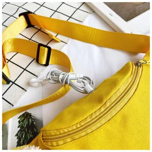 Detailed view of yellow canvas fanny pack featuring a functional earphone hole design.