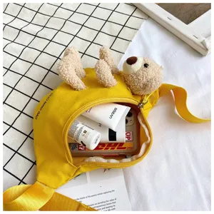 Close-up of yellow canvas waist bag with plush teddy bear detail and interior storage view