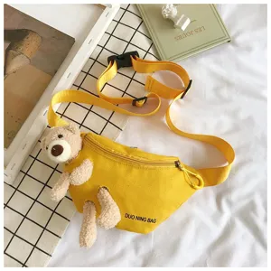 Detailed view of yellow canvas waist bag with cute plush teddy bear decoration.