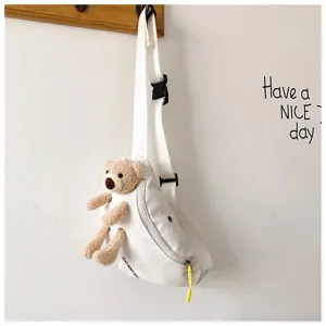White canvas chest bag featuring a cute plush bear detail hanging on a wall hook.