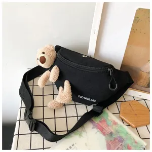 Detail view of the cute teddy bear plush attachment on a black canvas waist bag.