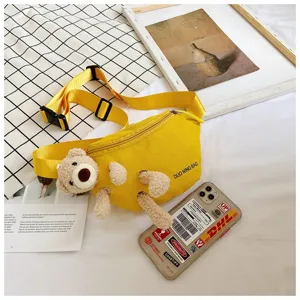 Close-up of yellow canvas fanny pack with a cute 3D plush teddy bear detail.