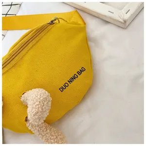 Close-up of vibrant yellow canvas waist bag featuring plush bear detail and Duo Ning Bag logo