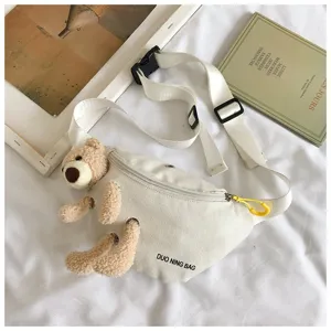 Detail view of the white canvas fanny pack with an adorable plush bear attached.