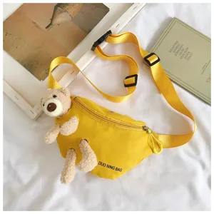 Detailed view of the yellow canvas chest bag with a cute plush bear attachment