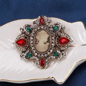 Detailed view of a vintage court style cameo brooch with red and green rhinestones.
