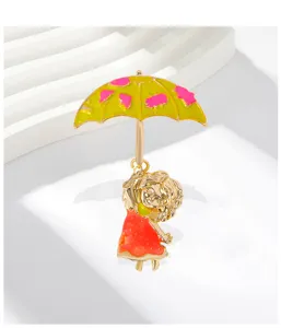 Dettaglio di una graziosa spilla in smalto con bambina e ombrello giallo, accessorio moda