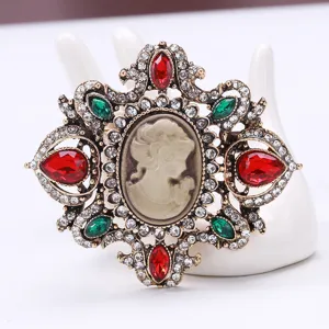 Detailed view of vintage cameo brooch with red and green stones on antique gold finish
