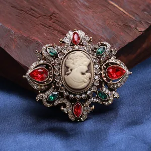 Detailed macro view of a vintage palace-style cameo brooch with red and green stones