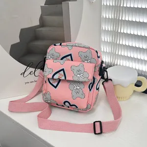 Detalle de un bolso bandolera de nailon rosa con lindos estampados de osos y corazones.