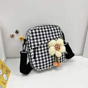 Vista detallada de un mini bolso bandolera a cuadros blancos y negros con flor de felpa.