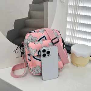 Bolso bandolera de nailon rosa con dibujos de osos, mostrado con un móvil para escala