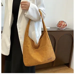 Detailed view of large yellow corduroy tote bag featuring an embossed brand leather patch.