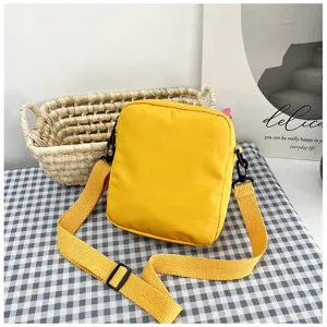 Bolso bandolera de lona amarillo vibrante para mujer en un mantel de cuadros azules