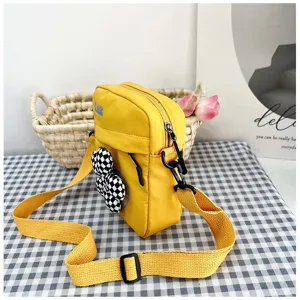 Vista lateral detallada del bolso bandolera amarillo estilo académico con lazo a cuadros