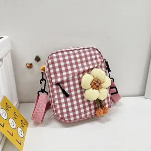 Primer plano del bolso bandolera a cuadros rosa con un gran adorno decorativo de flor amarilla