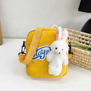 Primer plano de un bolso de lona amarillo con un lindo adorno de conejo de peluche