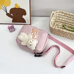 Primer plano de un bolso bandolera de nailon rosa con un lindo oso de peluche