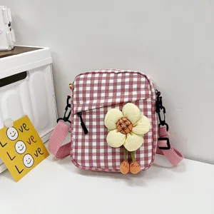 Vista detallada de un mini bolso bandolera a cuadros rojos y blancos con una flor de peluche.