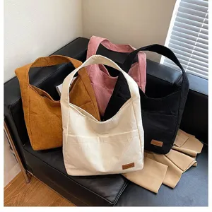 Large capacity corduroy tote bags in four stylish colors displayed on a modern black leather sofa.