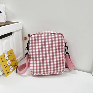Vista frontal de un mini bolso bandolera de cuadros rosa en una mesa blanca limpia